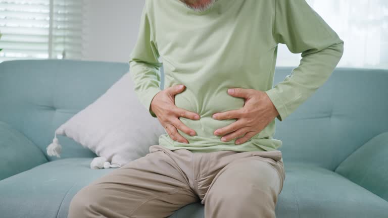 トイレで腹痛。腹を手でおさえて痛みをこらえる女性